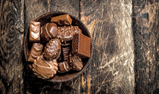 Caramelos de chocolate en un cuenco. Sobre una mesa de madera.