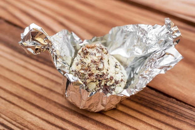 Caramelos de chocolate en una envoltura de lámina plateada sobre una mesa de madera Cerrar