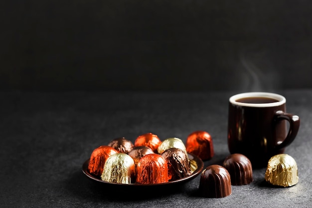 Caramelos de chocolate envueltos en papel multicolor y dos tazas de café.