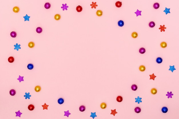 caramelos de chocolate, estrellas decorativas y copos de nieve sobre papel rosa