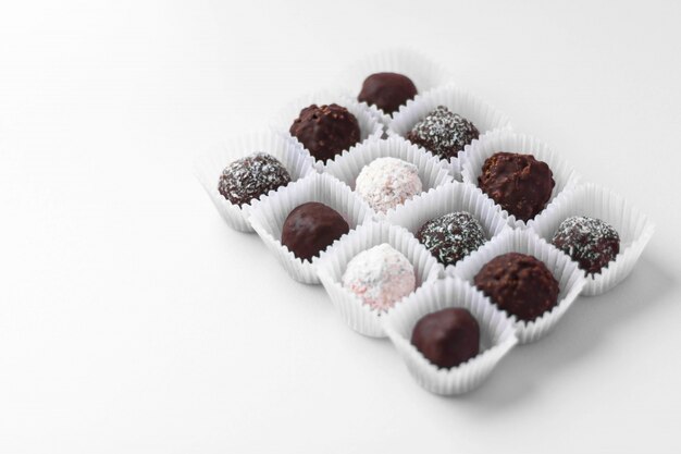 Caramelos de chocolate en forma de bola embalados en pequeñas cestas de papel aisladas sobre fondo blanco. Sabroso postre Dulce casero Estilo minimalista.