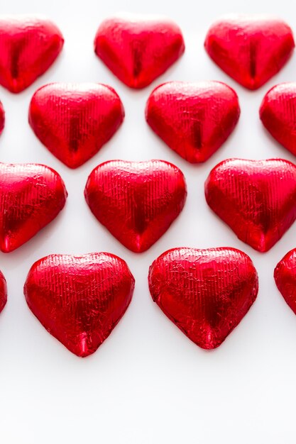 Caramelos de chocolate en forma de corazón sobre fondo blanco.