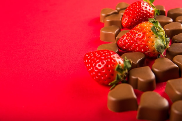 Caramelos de chocolate y fresas sobre fondo rojo, día de San Valentín