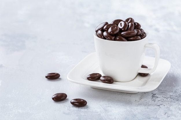 Caramelos de chocolate negro en taza de café blanco