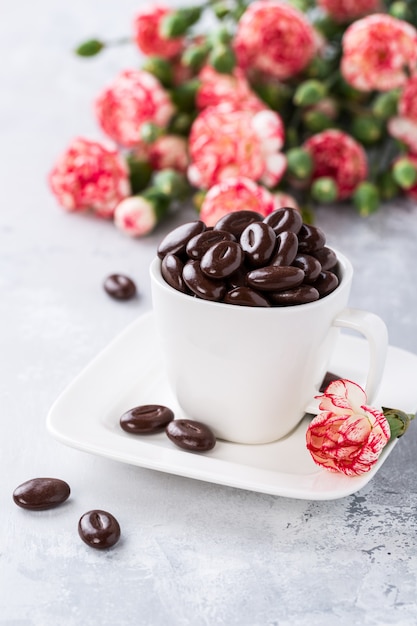 Caramelos de chocolate negro en taza de café blanco