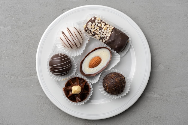 Caramelos de chocolate en un plato blanco sobre fondo gris