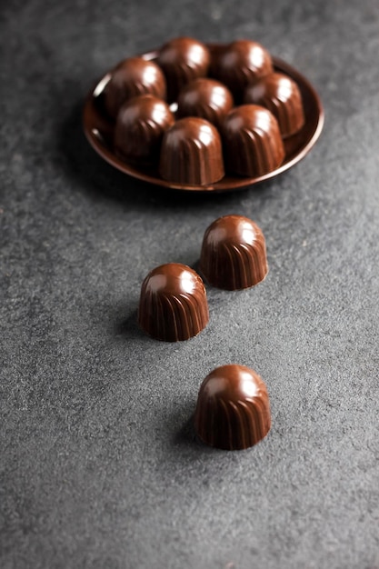 Caramelos de chocolate en un plato sobre fondo negro con espacio de copia