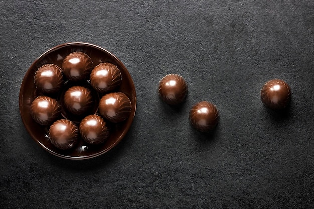 Caramelos de chocolate en un plato sobre fondo negro con espacio de copia