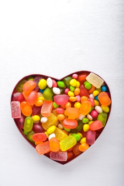 Caramelos de colores dulces y piruletas Sobre un fondo blanco de madera Vista superior Espacio libre