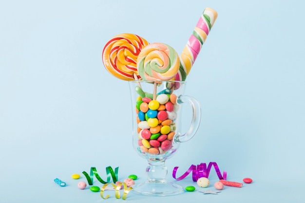Caramelos coloridos en taza en la mesa sobre un fondo claro Granos piruletas giratorias Concepto creativo de un frasco lleno de deliciosos dulces de la tienda de caramelos
