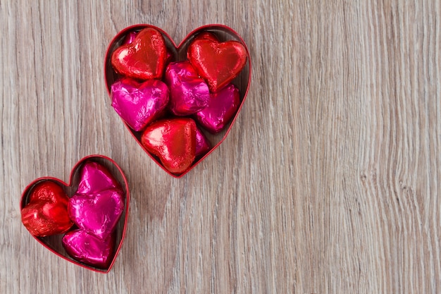 Caramelos de corazón rojo y rosa sobre mesa de madera