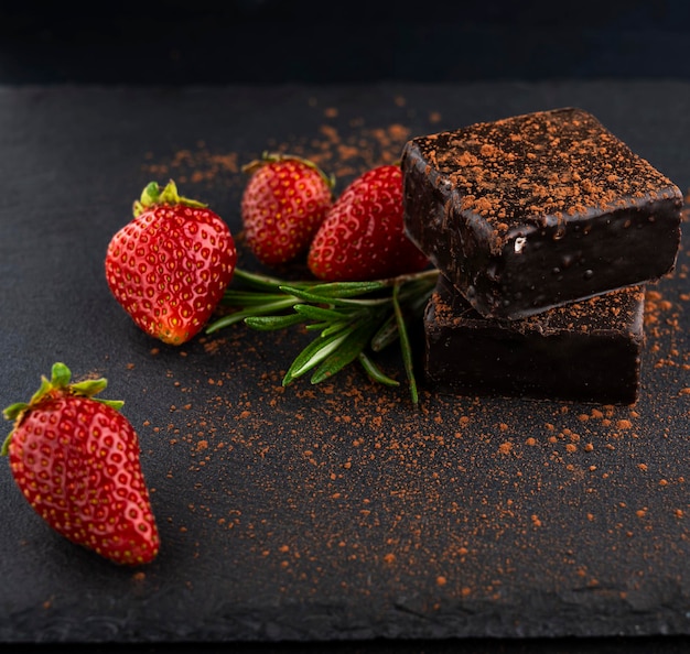 Caramelos dulces espolvoreados con cacao y junto a fresas Delicioso postre Leche de pájaro en choco