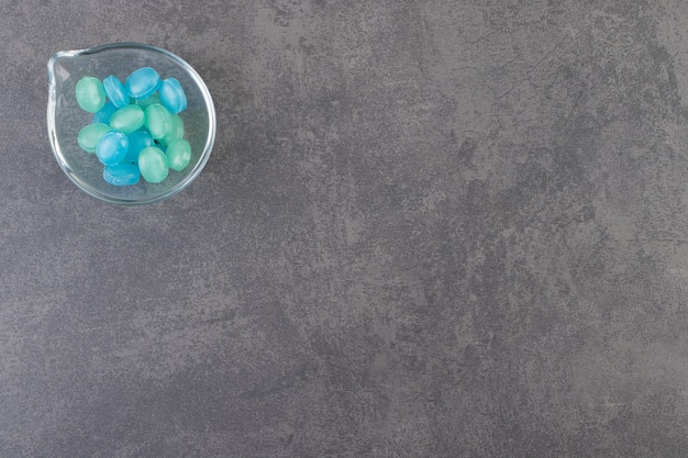 Caramelos duros azules y verdes en un recipiente colocado sobre la mesa de piedra.