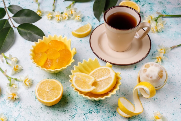 Caramelos de gelatina de limón con limones frescos sobre hormigón, vista superior