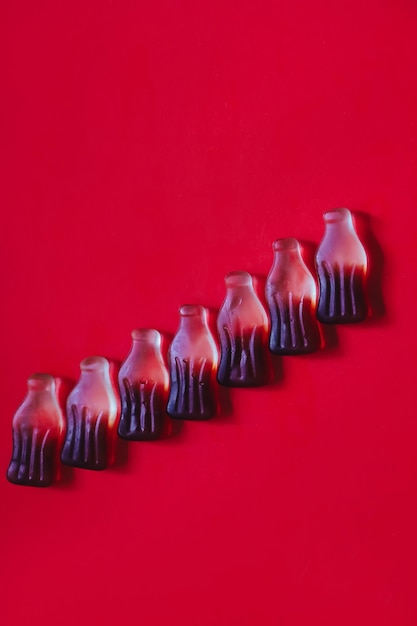 Foto caramelos gomosos de gelatina en fila en forma y sabor de botellas de cola