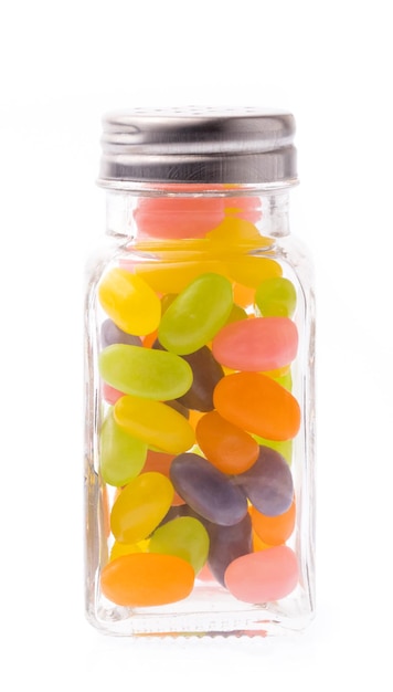 Caramelos de Jelly Bean en botella de vidrio aislado sobre fondo blanco.