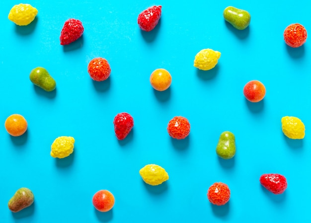 Caramelos masticables brillantes en forma de frutas esparcidas sobre un fondo azul. Vista superior. Fondo de dulces creativos.