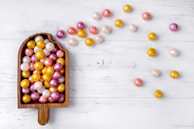 Caramelos redondos de colores mezclados sobre fondo blanco de madera Vista superior plana Lugar para el texto