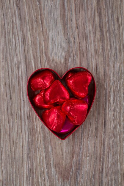 Caramelos rojos en corazón sobre mesa de madera