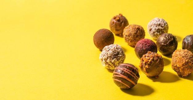 Caramelos de trufa de chocolate con varios rellenos sobre un fondo amarillo brillante