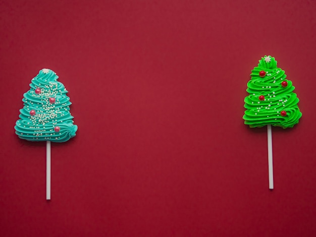 Caramelos verdes y azules bajo la forma de árbol de navidad en un fondo rojo