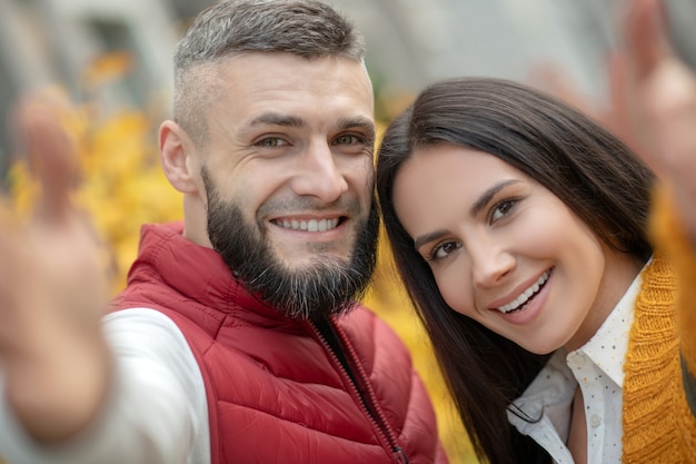 Caras de positivo feliz joven y mujer sonriendo a la cámara