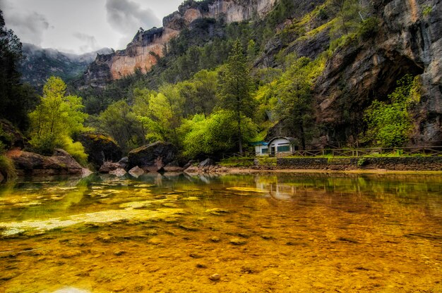 Una caravana está estacionada en un río frente a una montaña.