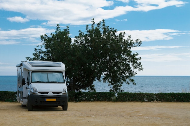 Caravana de remolque de viaje estacionada en un hermoso camping con vista a la costa costera