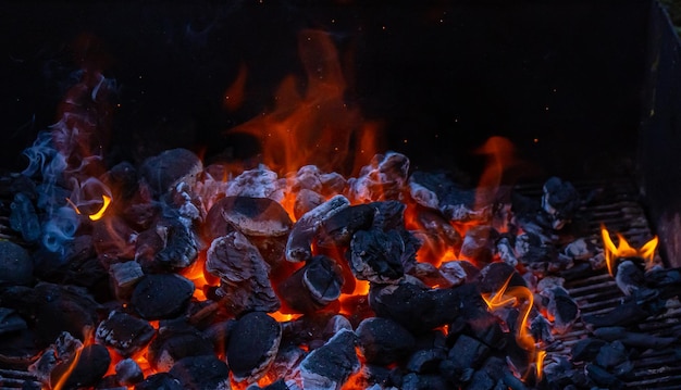 Foto carbón y brasas ardiendo a pleno rendimiento en su punto máximo en una barbacoa metálica