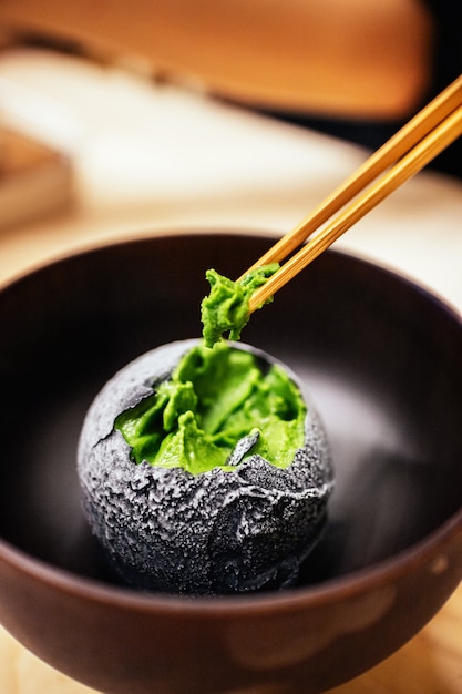 El carbón cubría una bola de helado de té verde que pellizcaba con palillos.