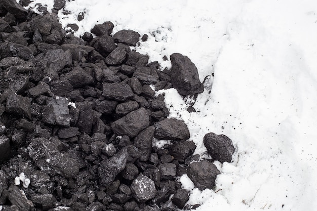 Carbón grueso en la nieve en invierno. Mantenimiento de altas temperaturas en calderas de combustible, sistemas de calefacción doméstica. Mineral combustible.