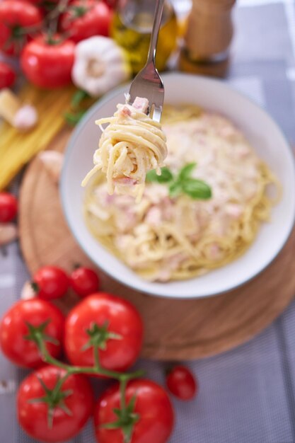 Carbonara de pasta casera con albahaca fresca y parmesano en plato de cerámica