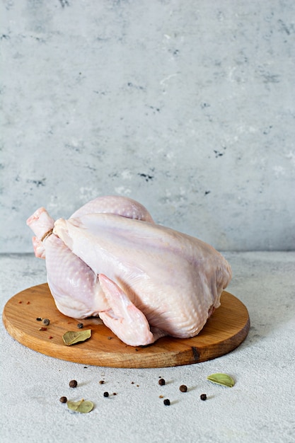 Carcaça de frango cru pronto para cozinhar em uma tábua em um fundo cinza