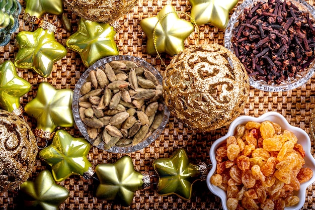 Cardamomo de pasas doradas y clavos con adornos de árboles de Navidad en un fondo amarillo