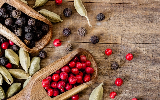 Cardamomo con pimienta negra y rosa en cucharas de madera