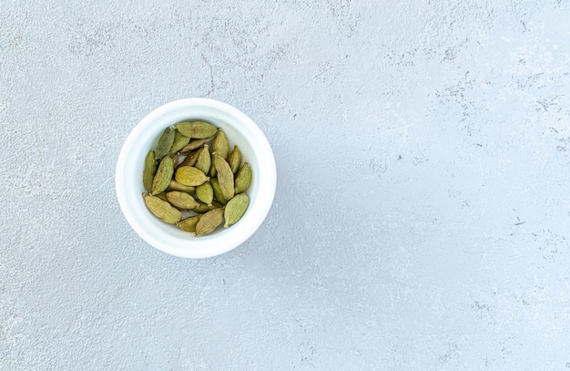 Cardamomo en un plato blanco sobre un fondo gris Foto de alta calidad