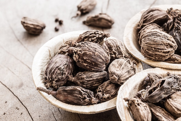 Cardamomo todo preto na tigela de coco em fundo de madeira