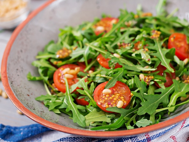 Cardápio dietético. Cozinha vegana. Salada saudável com rúcula, tomate e pinhões.