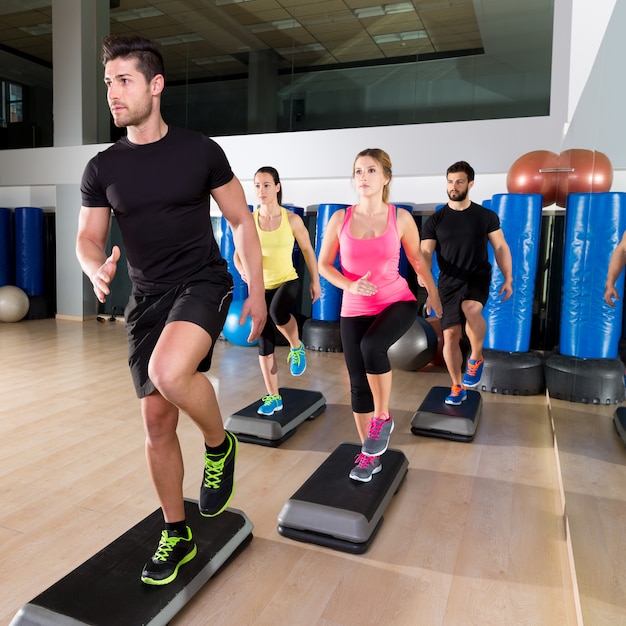 Cardio paso grupo de baile en el entrenamiento de gimnasio de fitness