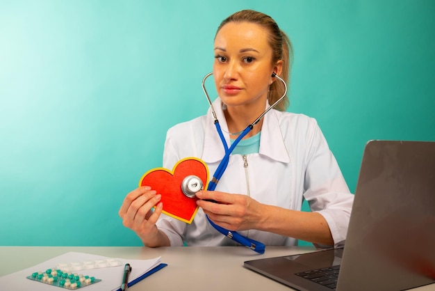 Foto cardiólogo con modelo de corazón y estetoscopio en el concepto de ataque al corazón de su oficina