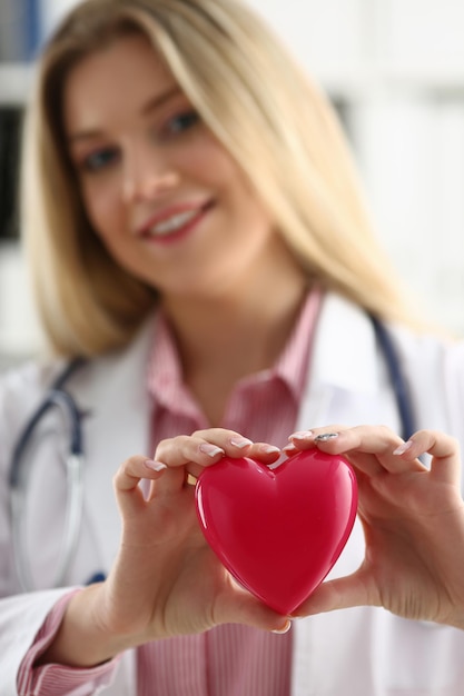 Foto el cardiólogo tiene el corazón rojo en las manos de cerca