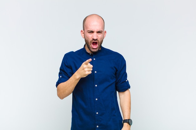 Careca apontando para a câmera com uma expressão agressiva e raivosa, parecendo um chefe louco e furioso