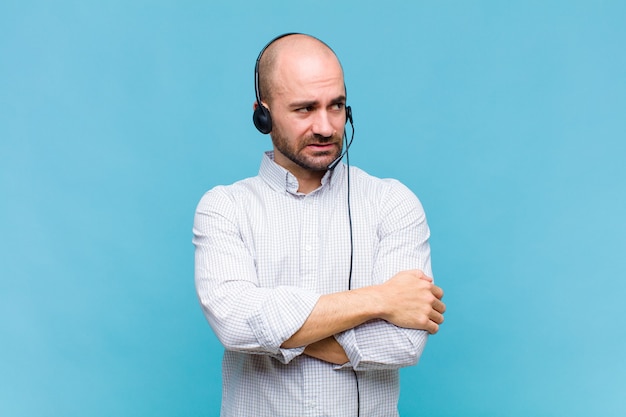 Careca duvidando ou pensando, mordendo o lábio e sentindo-se inseguro e nervoso, procurando copiar o espaço ao lado