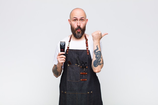 Careca parecendo espantado em descrença, apontando para o objeto ao lado e dizendo uau, inacreditável