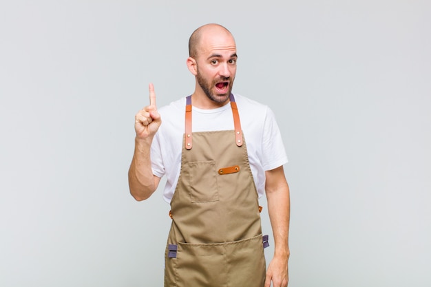 Careca se sentindo um gênio feliz e empolgado depois de realizar uma ideia, levantando o dedo alegremente, eureka!