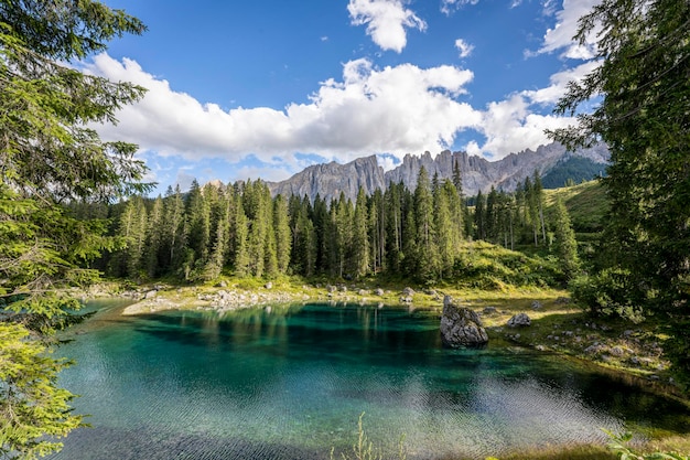 Carezza Lake an einem sonnigen Tag mit etwas Wolken