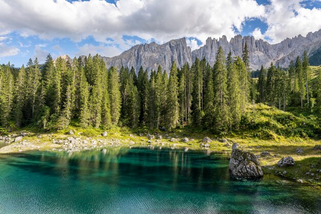 Foto carezza lake an einem sonnigen tag mit etwas wolken