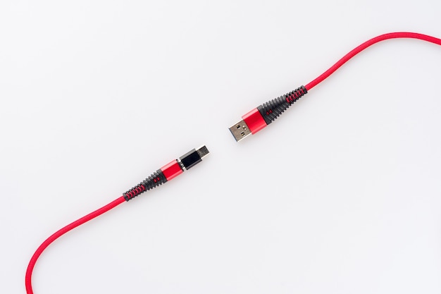 Carga de cable rojo y conexión de un teléfono inteligente USB en un blanco