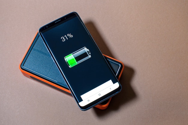 Carga de smartphone con paquete de energía solar naranja, nivel de carga.