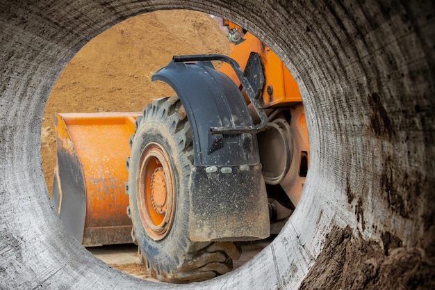 El cargador de la excavadora trabaja con un cucharón para transportar arena en un sitio de construcción Equipo de construcción profesional para movimiento de tierras